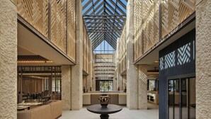 A spacious atrium with a central table, high ceilings with geometric patterns, and a seating area with tables and chairs. - Amoh, A Luxury Collection Resort, Rhodes (Rhodes)