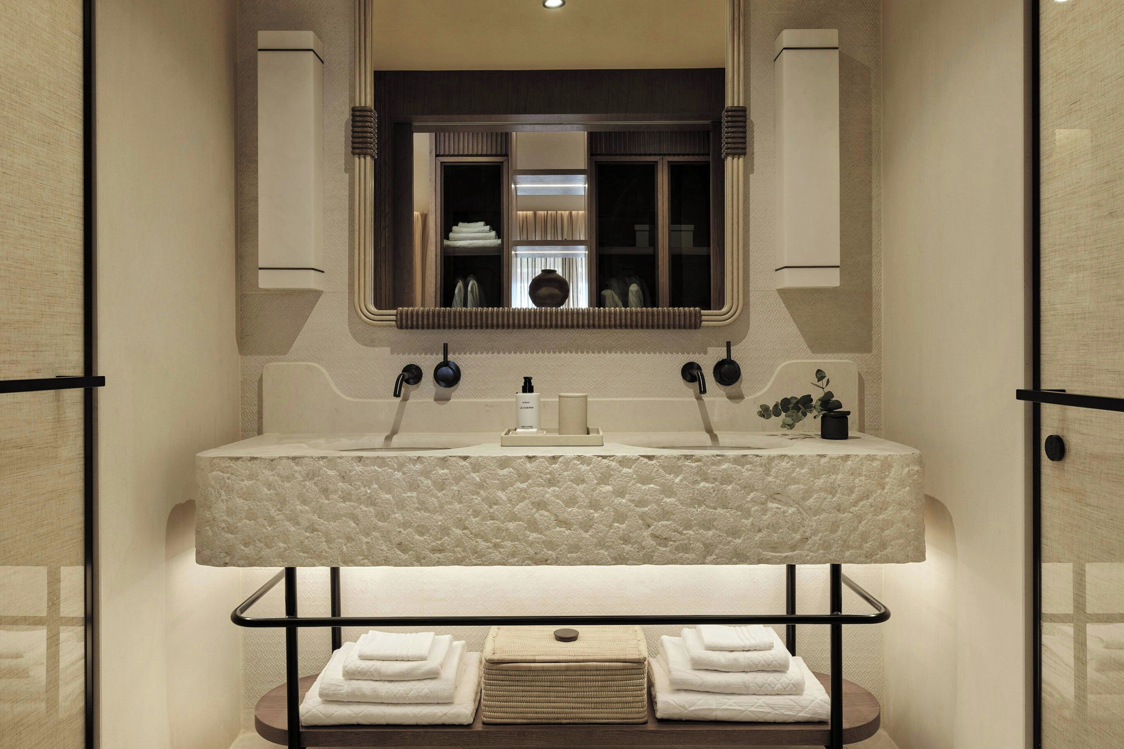 A bathroom with a large mirror, a rectangular sink, and a towel rack with folded towels.