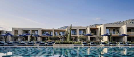 A hotel with a swimming pool, sun loungers, and umbrellas.