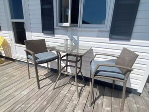 Eine Terrasse mit Korbstühlen und einem Glastisch.