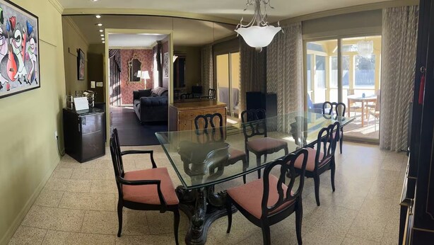 A dining area with a glass table and chairs, a sofa, and a television in the background. - Spacious 7-bedroom house on quiet cul-de-sac in heart of Plattsburgh (Plattsburgh)