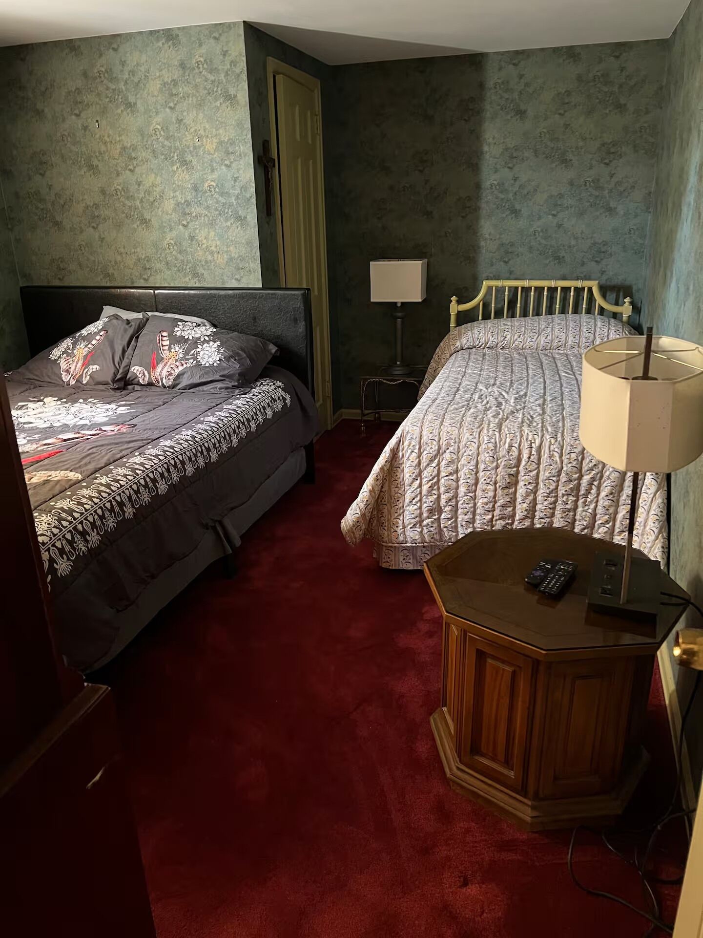 Ein Hotelzimmer mit zwei Betten, einem Holznachttisch, einer Lampe und einem kleinen Tisch mit Fernbedienung.