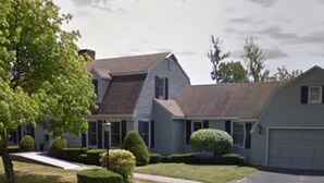 A two-story residential house with a front garage, a well-maintained lawn, and a driveway leading to the garage. - Spacious 7-bedroom house on quiet cul-de-sac in heart of Plattsburgh (Plattsburgh)