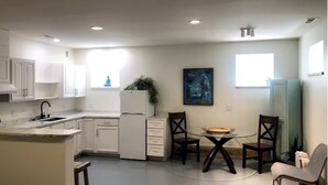 A modern kitchen with white cabinets, a built-in oven, and a dining area with a glass table and chairs.