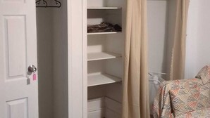 A room with a white door, a closet with shelves, a bed with a patterned bedspread, and a black rug. - Whole House: Fair Price Great Amenities (Richmond Hill)