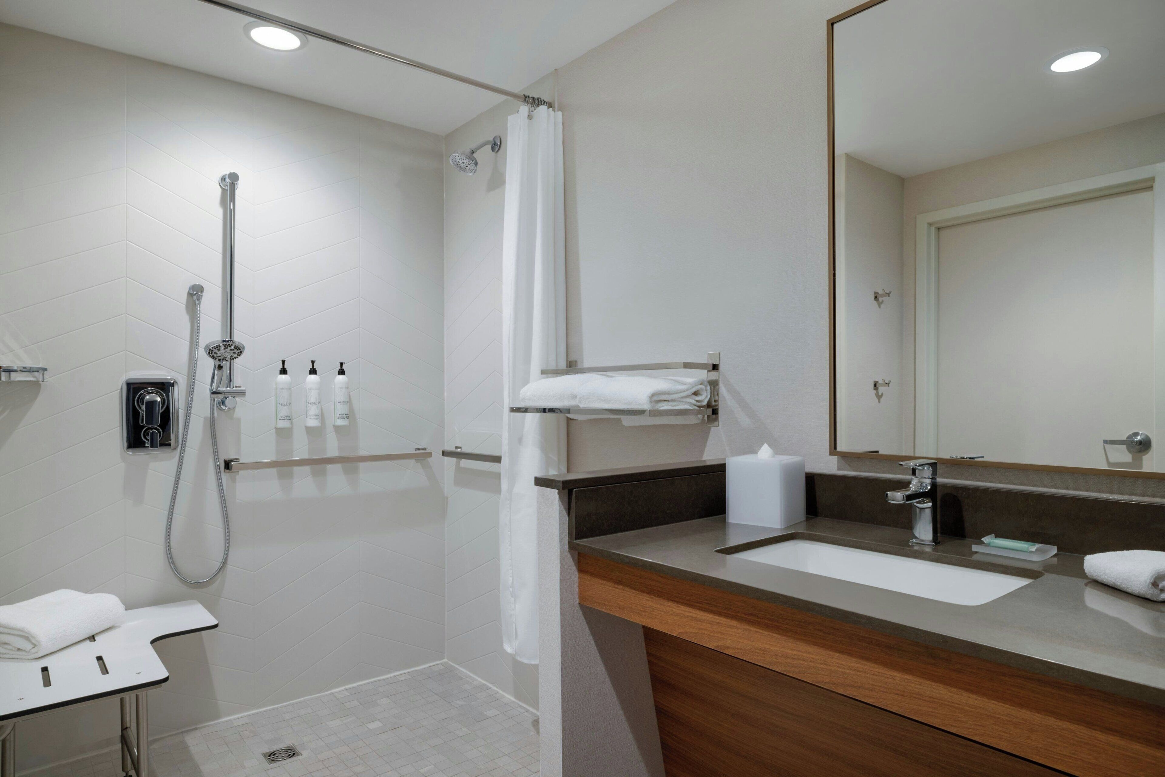 Une salle de bain moderne avec une douche, un lavabo et un miroir.