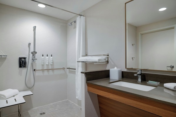 Un baño moderno con ducha, lavamanos y espejo.