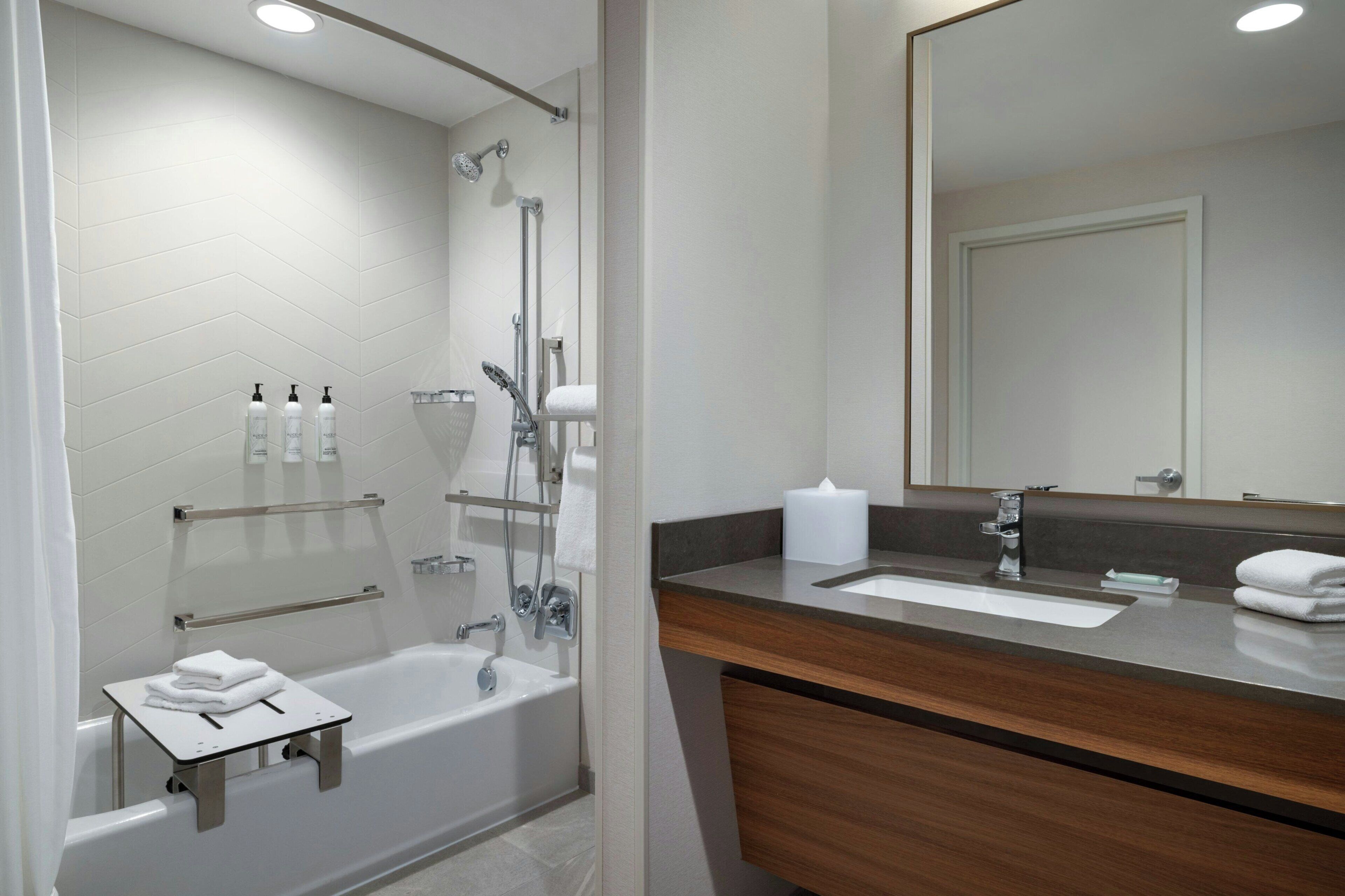 Un baño moderno con bañera, ducha, tocador y un espejo grande.