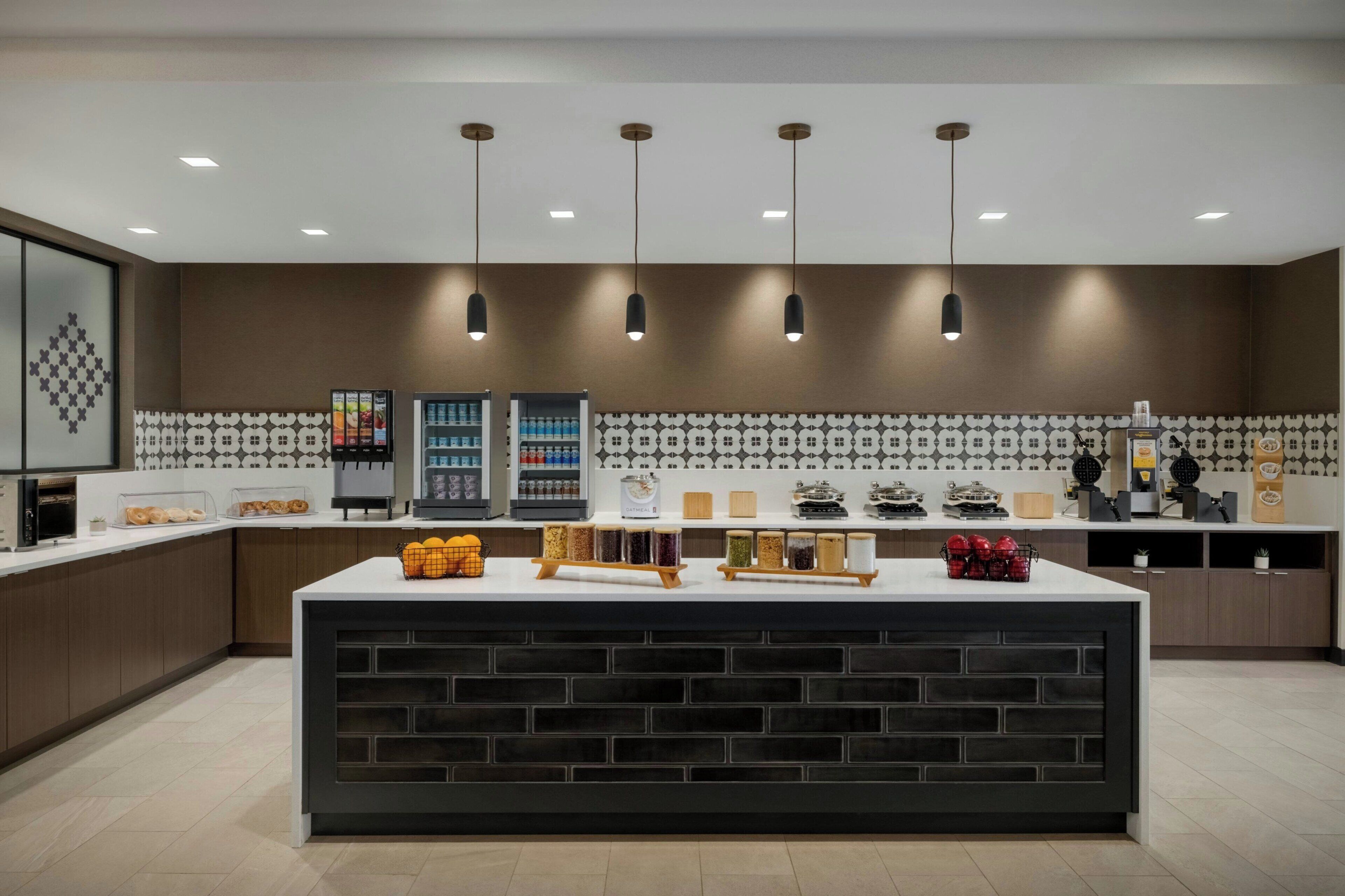 A modern kitchen with a central island, built-in appliances, and a patterned backsplash.