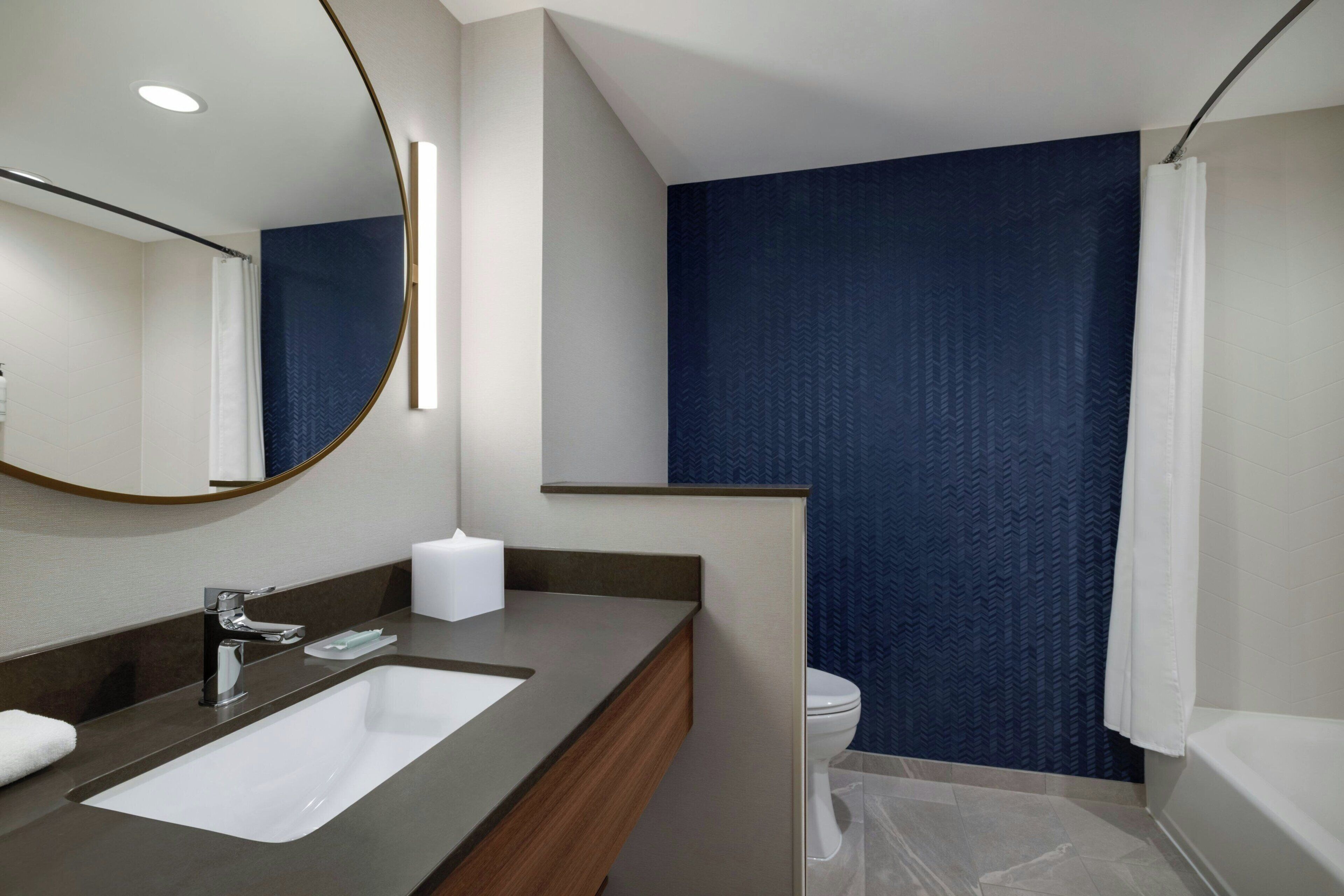 A modern bathroom with a large sink, mirror, and a shower area.