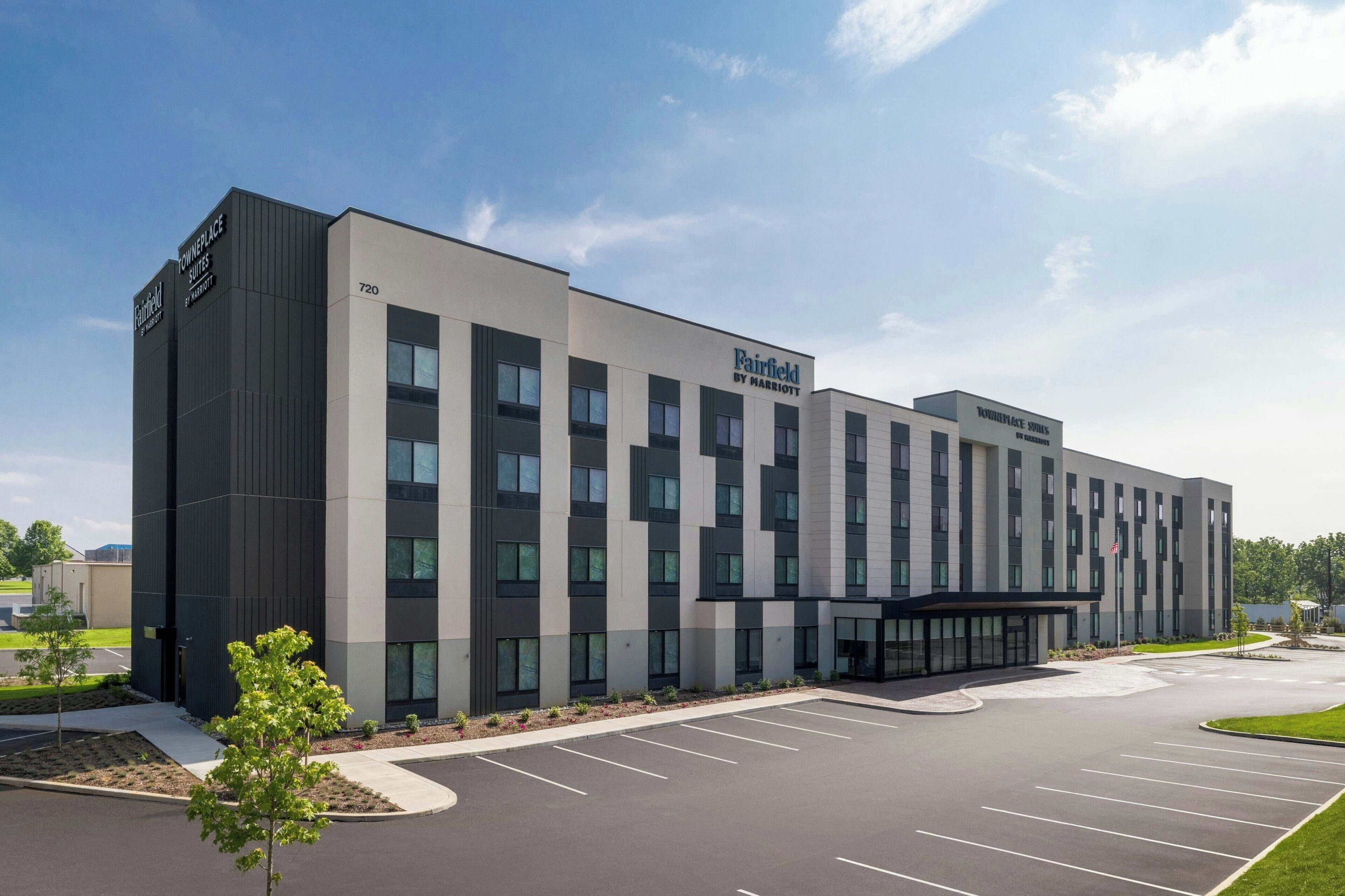 A modern hotel with a flat facade, multiple windows, and a parking lot.