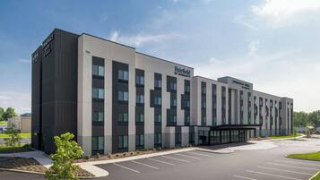 A modern hotel with a flat facade, multiple windows, and a parking lot.