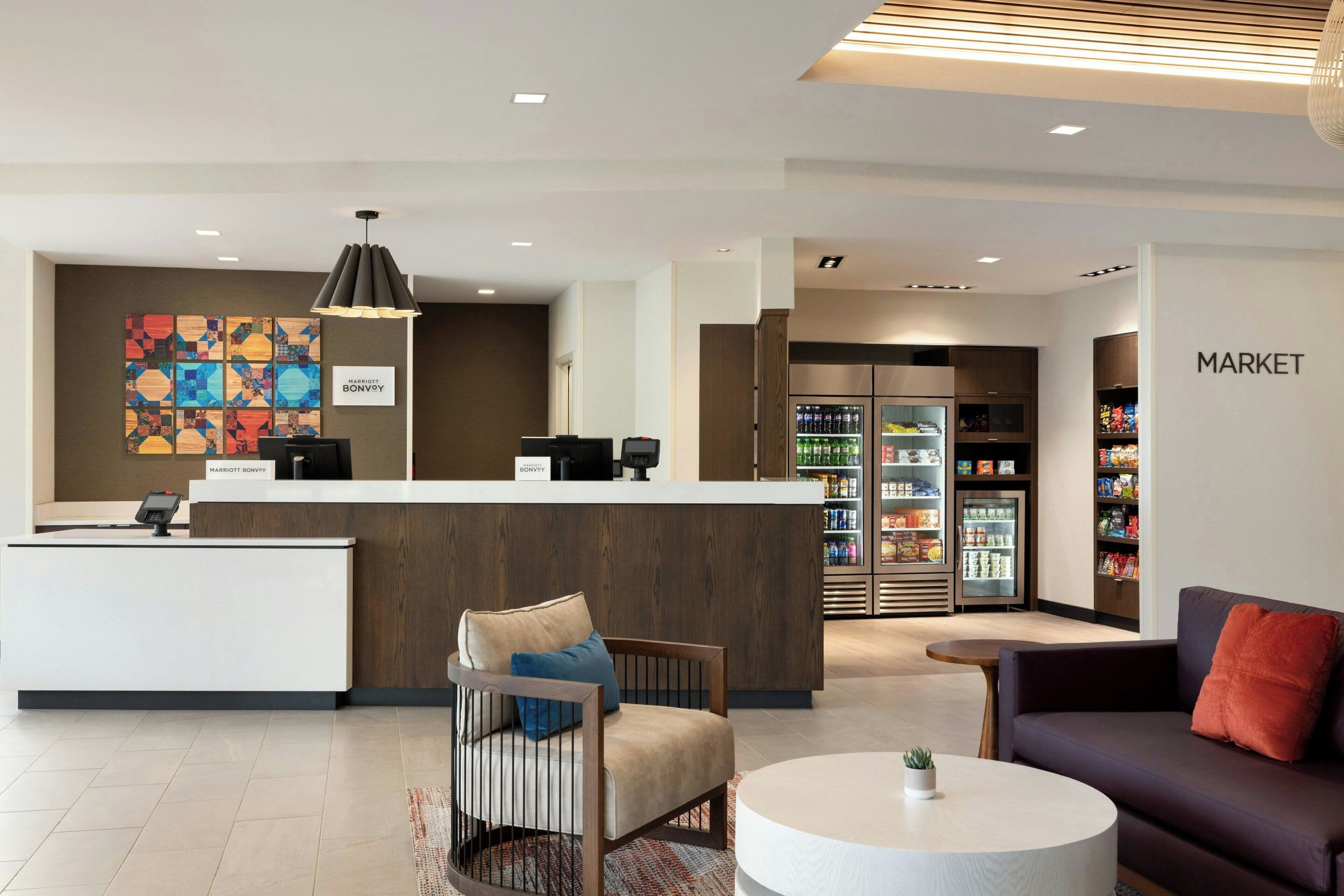 A hotel lobby with a reception desk, seating area, and a market.