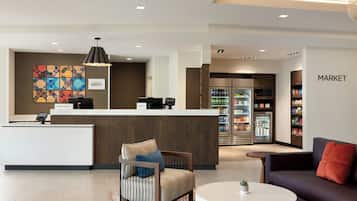 A hotel lobby with a reception desk, seating area, and a market.