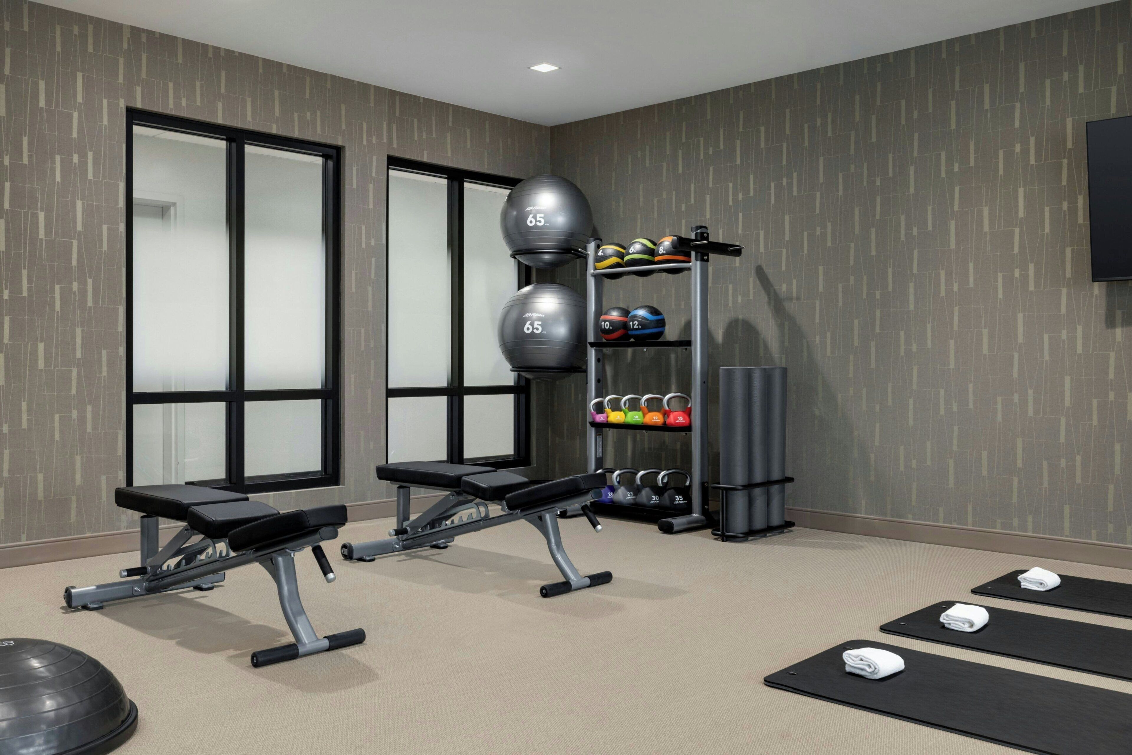 A gym with exercise equipment, weight plates, and mats.