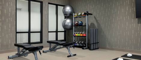 A gym with exercise equipment, weight plates, and mats.
