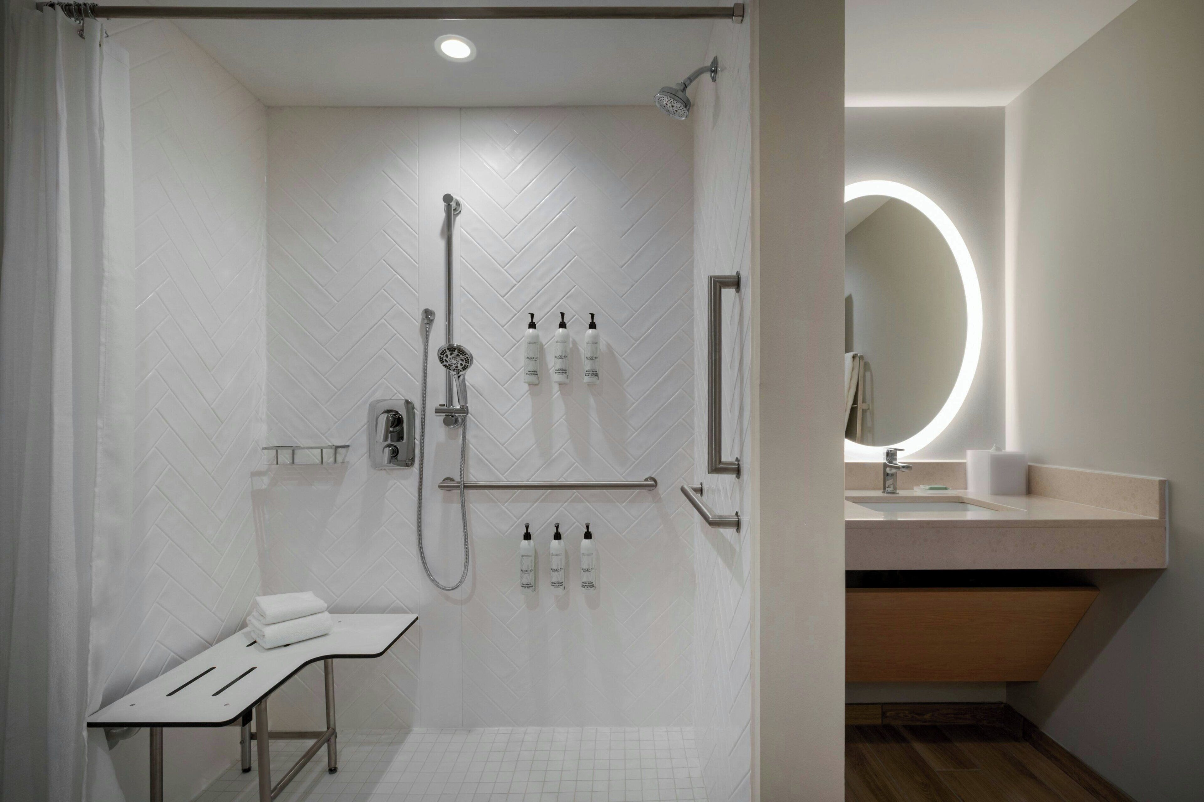 A modern bathroom with a shower, toilet, and sink, featuring a herringbone tile pattern and a wooden vanity.