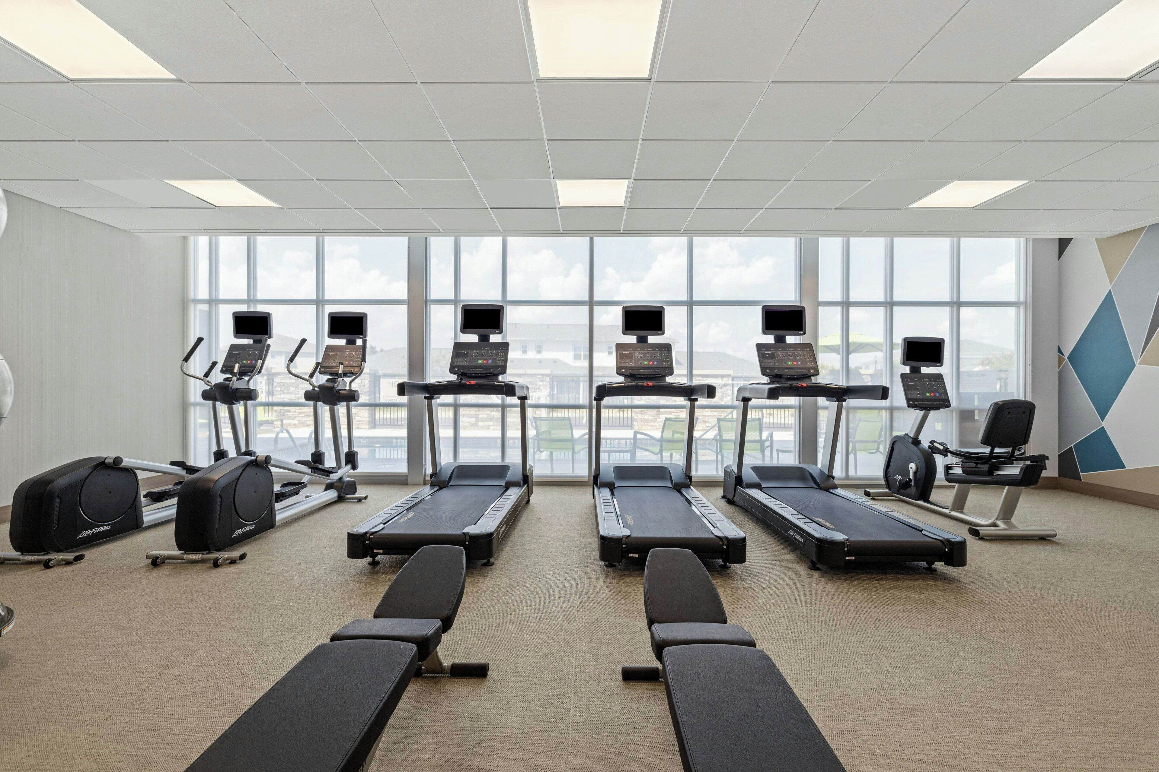Ein Fitnessstudio mit Laufbändern, Crosstrainern und Rudergeräten.
