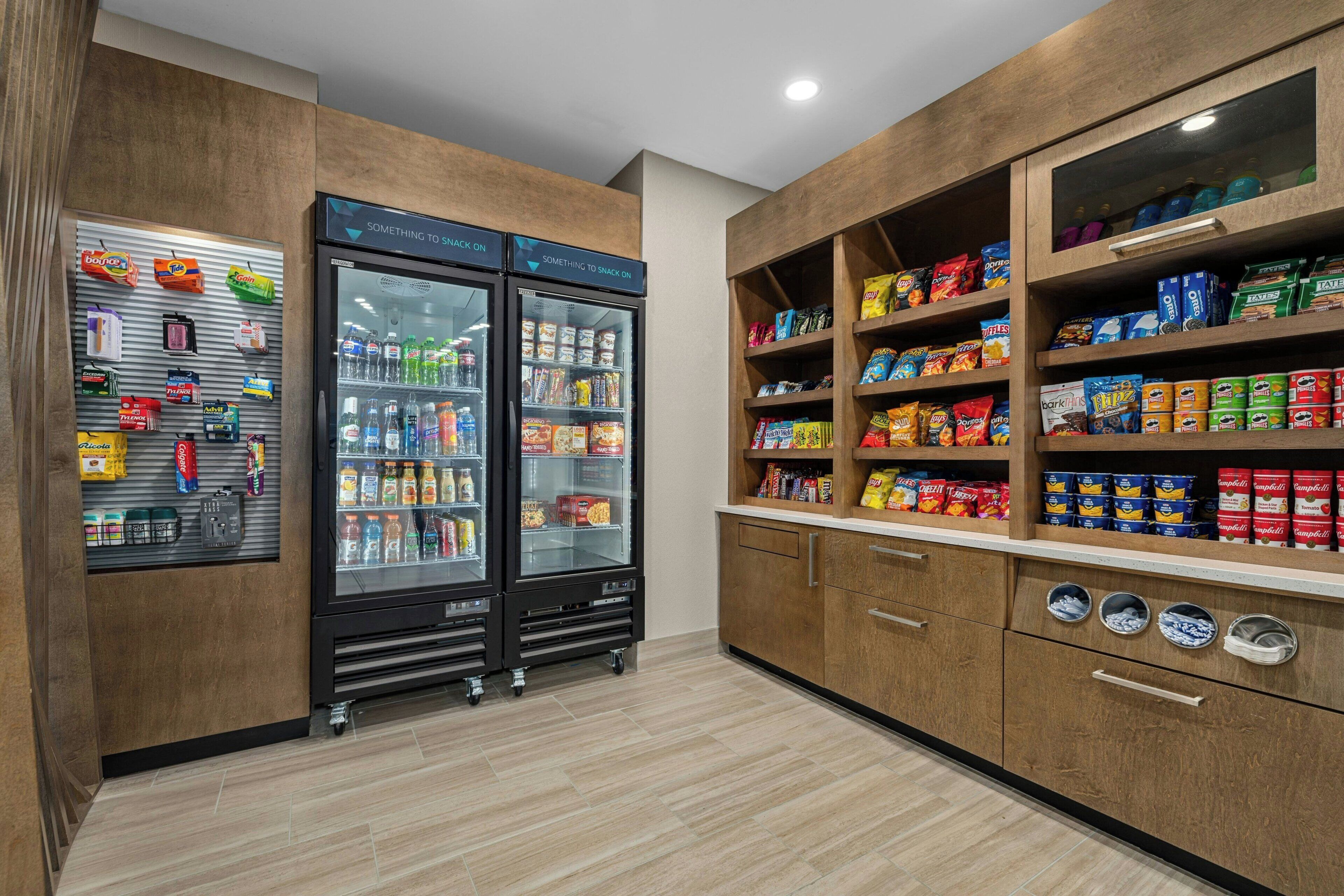 Un mostrador de bar con refrigeración y estantes, que ofrece una variedad de aperitivos y bebidas.