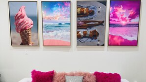 A white sofa with pink and silver fluffy pillows, and three framed artworks above it. - Perfect getaway in Corktown! (Detroit)