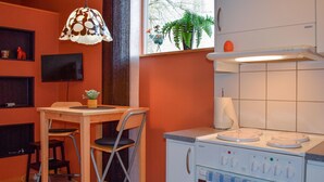 A compact kitchen with a Siemens stove, a small dining table with chairs, a hanging pendant light, and a window with a view of trees and a plant. - Pet friendly apartment in Kristianstad (Kristianstad)