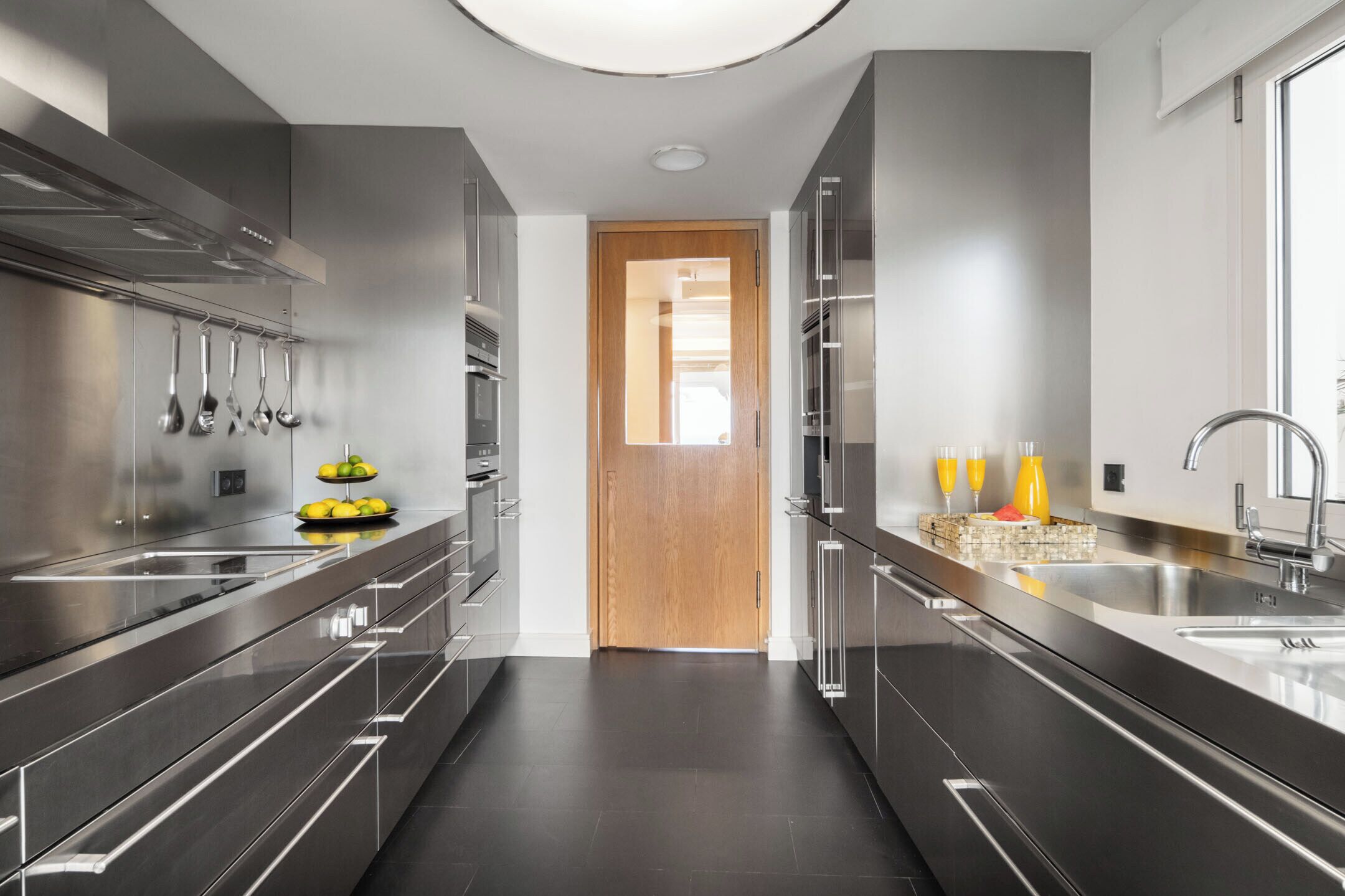A modern kitchen with stainless steel appliances, a central island, and a view through a doorway.