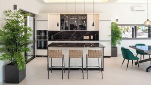 A modern kitchen with a central island, bar stools, and pendant lighting.