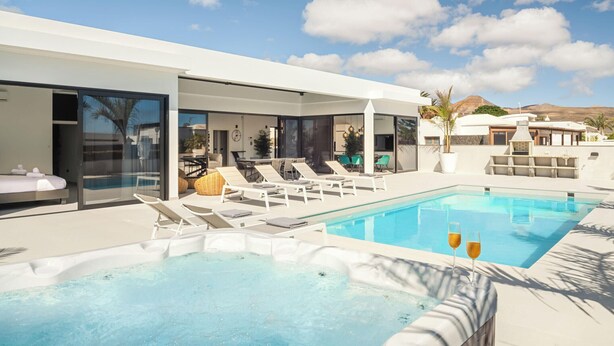 A modern pool area with lounge chairs, a hot tub, and a clear view of the surrounding landscape.