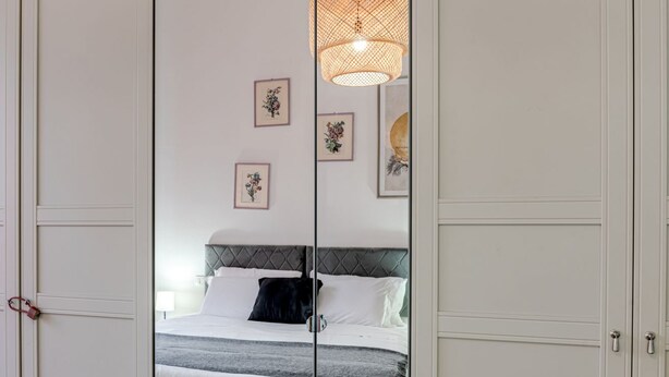 Une chambre à coucher avec un lit, un luminaire suspendu et des tableaux encadrés accrochés au mur.