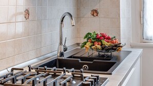 Une cuisine moderne équipée d’une cuisinière à gaz, d’un évier en acier inoxydable et d’un panier à fruits posé sur le plan de travail.