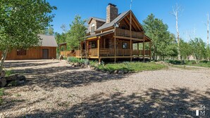 Une cabane en rondins avec un porche, une cheminée et une allée gravillonnée.