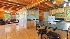L’intérieur d’une cabane en rondins comprend une cuisine, un coin repas et un salon.