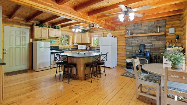 L’intérieur d’un chalet en bois comprend une cuisine, un coin repas et une cheminée en pierre.
