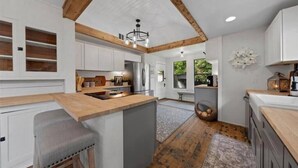Una cocina moderna con armarios blancos, techo de madera y una isla central.