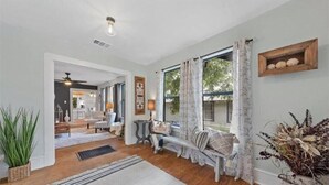 Un salón amplio con un gran ventanal, un rincón de estar acogedor y suelo de madera.