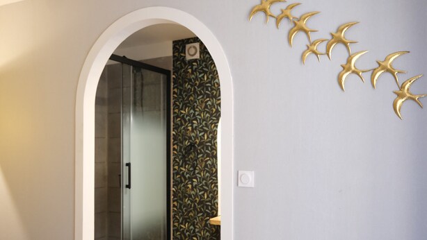 Une salle de bain avec une porte de douche en verre, un mur à motifs et un élément décoratif mural.