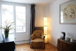 Ein Zimmer mit Stuhl, Lampe, Schrank und einem Fenster mit Vorhängen.
