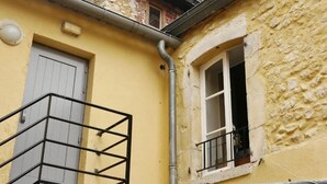 Un bâtiment jaune avec une porte blanche et une fenêtre dotée d’un garde-corps noir.