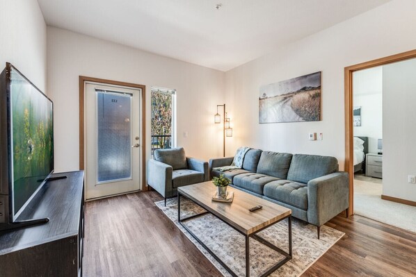 Una sala moderna con un sofá, un sillón, una mesa de centro y un televisor.