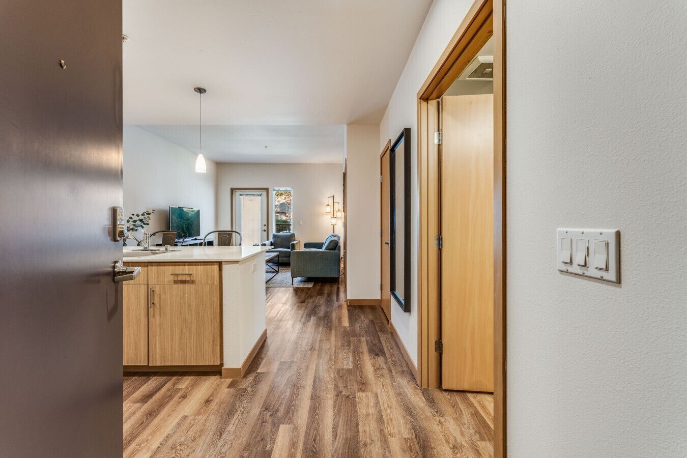 Une cuisine moderne avec des meubles en bois, un îlot central et un coin repas comprenant un canapé et des chaises.