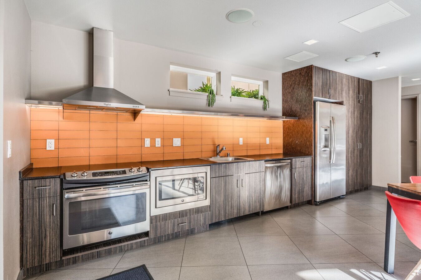 A modern kitchen with stainless steel appliances, wooden cabinetry, and a tiled backsplash.
