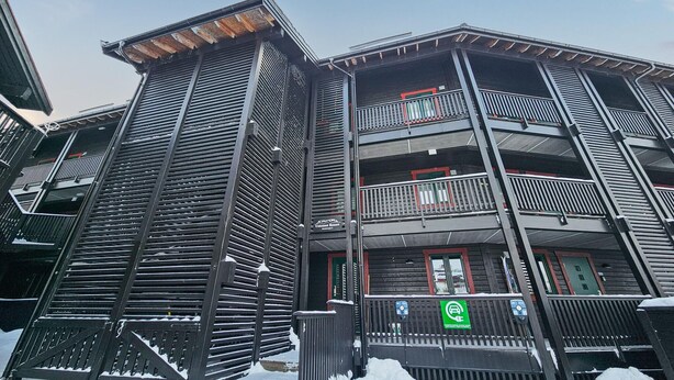 A multi-story building with balconies, a ski resort sign, and a green parking sign.