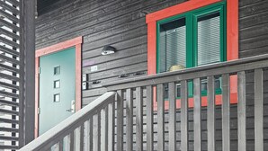 A wooden building with a green door and red-framed windows.