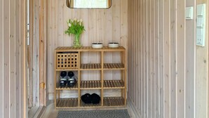A wooden shelf unit with shoes, a vase with green plants, and two bowls. - Stunning home in Frørup with WiFi (Frørup)