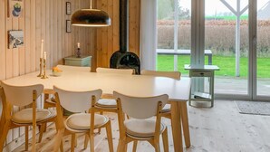 A dining area with a white table and six chairs, a pendant light, and a view of a garden through large windows. - Stunning home in Frørup with WiFi (Frørup)