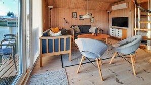 A cozy cabin interior with a wooden ceiling, a TV, a sofa, a coffee table, and a dining area. - Stunning home in Frørup with WiFi (Frørup)