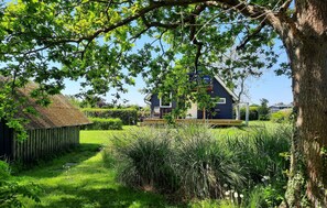 A house with a thatched roof, surrounded by lush greenery and a clear sky. - Stunning home in Frørup with WiFi (Frørup)