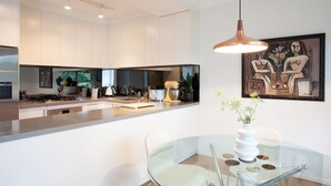 Une cuisine moderne dotée d’un îlot central, d’appareils électroménagers en acier inoxydable et d’un luminaire suspendu.