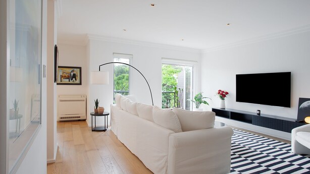 Un salon moderne avec un canapé blanc, un téléviseur à écran plat et une grande fenêtre.
