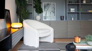 Un salon moderne avec un canapé blanc, un tapis à rayures, une carte de New York et une plante.